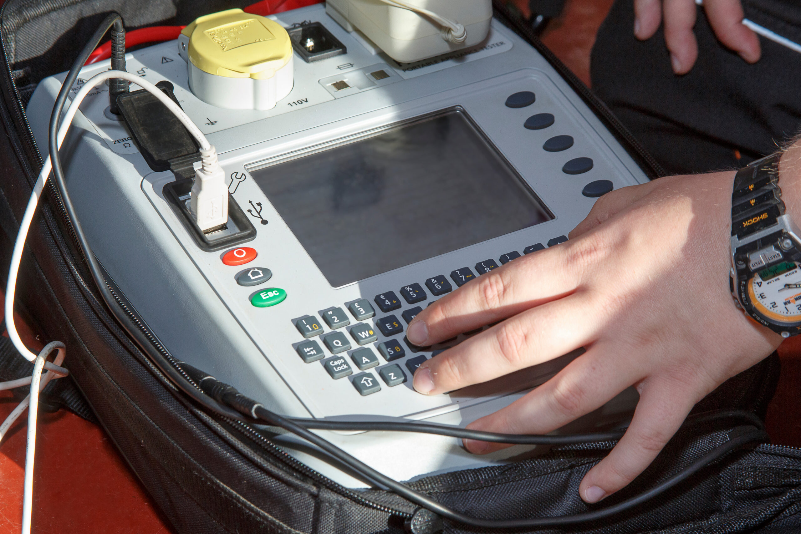 Electrician using PAT - (portable appliance testing)Testing machine